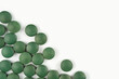 Spirulina tablets frame on white background. Nutrition, vitamin, immunity concept. Top view, flat lay, copy space