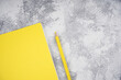 Yellow notebook and pencil on light gray concrete background. Colors of the Year 2021, workplace concept. Top view, flat lay, mockup, copy space