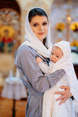 Sticker - beautiful mom in a headscarf with a small child in her arms in church. 