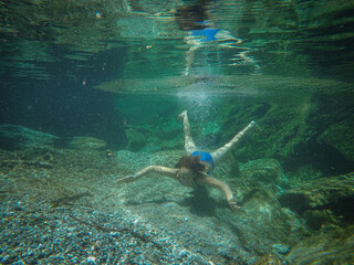 Wall Mural - girl swims in the crystal clear green water