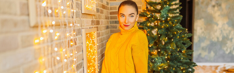 Wall Mural - Beautiful cheerful happy young girl with christmas gifts on the background of a new year tree at home