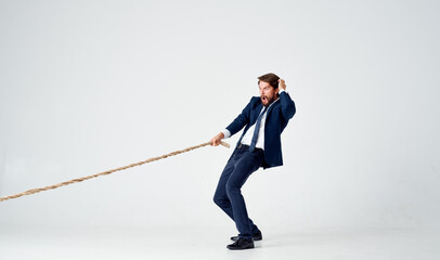 Poster - business man with a rope in his hands on a light background tension model of achieving the goal