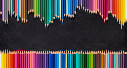 Wave border of colorful wooden pencils on a blank blackboard, back to school concept.