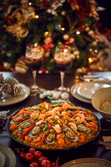 Spanish dinner table with assortment of dishes. paella, octopus, whole fish, sangría and wine. Dressed for christmas