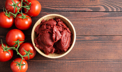 Traditional turkish tomato paste in bowl or spoon with fresh tomatoes on wooden table, homemade healthy food