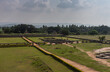 Hampi, Karnataka, India - November 4, 2013: Royal Enclosure. Stepped tank in wider grassy area with also lower walls and other ruins under light blue sky.