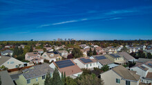 Suburban Homes With Solar Panels With Downtown High Rise Buildings In The Distance 