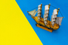 Layout Of Travel Theme. Model Of Sailing Ship Made Of Wood In Blue Sea, Ocean, Standing, Moored To Sea Shore With Yellow Sand. Layout Of Sea And Yellow Beach With Sailing Ship. Copy Space For Text