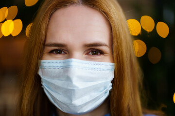 portrait of a woman in a disposable protective medical mask. garland lights.