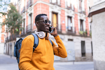 Wall Mural - Black Man Having Phone Call Wearing Yellow Sweater Outdoors.