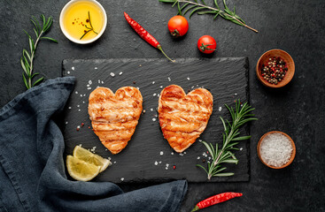 Two grilled salmon fillets with heart shaped spices for valentine's day on stone background