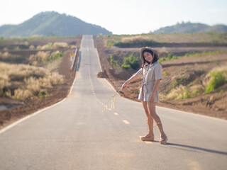 Wall Mural - A woman wearing a hat and glasses is standing in the middle of the road.