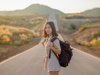 Wall Mural - A woman with a backpack standing in the middle of the road