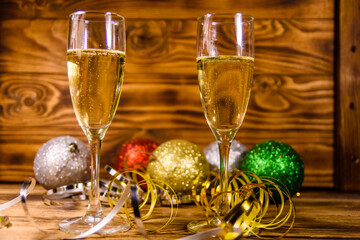 Wall Mural - Two wineglasses with champagne and different christmas decorations on wooden table