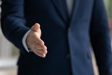 Wall Mural - Close up businessman wearing suit extending hand for handshake to business partner or customer at meeting, hr manager greeting candidate at job interview, first impression or acquaintance