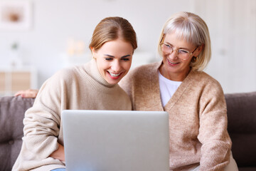 cheerful mother and daughter using laptop together