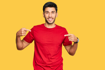 Young handsome man wearing casual red tshirt looking confident with smile on face, pointing oneself with fingers proud and happy.