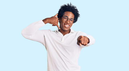 Wall Mural - Handsome african american man with afro hair wearing casual clothes and glasses smiling doing talking on the telephone gesture and pointing to you. call me.