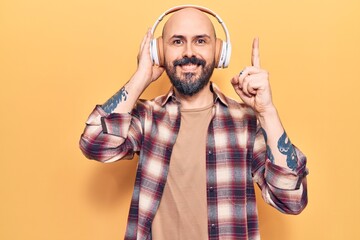 Poster - Young handsome man listening to music using headphones smiling with an idea or question pointing finger with happy face, number one