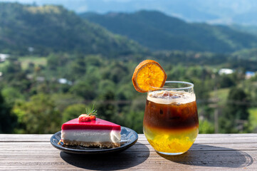 Wall Mural - Black coffee orange mixed juice in glass and strawberry cake with mountains view