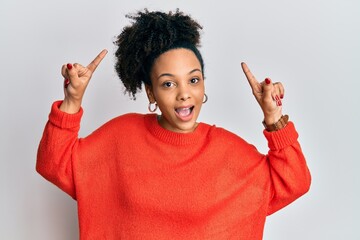 Canvas Print - Young african american girl wearing casual clothes smiling amazed and surprised and pointing up with fingers and raised arms.