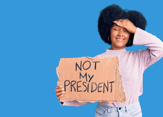 Wall Mural - Young african american girl holding not my president protest banner stressed and frustrated with hand on head, surprised and angry face