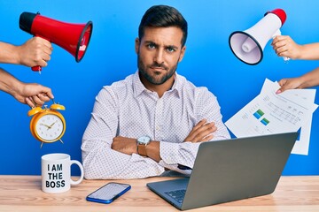 Handsome hispanic man working at the office being stressed out skeptic and nervous, disapproving expression on face with crossed arms. negative person.