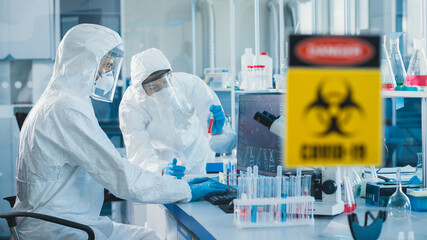 medical laboratory team of microbiology scientists wearing sterile coveralls, face shields and masks