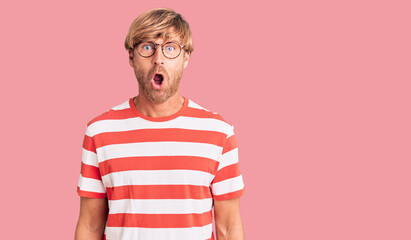 Canvas Print - Handsome caucasian man with beard wearing casual clothes and glasses afraid and shocked with surprise expression, fear and excited face.