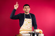 © Viorel - A man with an idea to cook dinner, index finger up. Pink background. Gender equality concept.