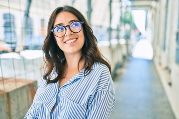 Wall Mural - Young hispanic businesswoman smiling happy walking at the city