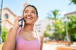 © Krakenimages.com - Young beautiful hispanic sporty woman wearing fitness outfit smiling happy and natural calling using smartphone at the town