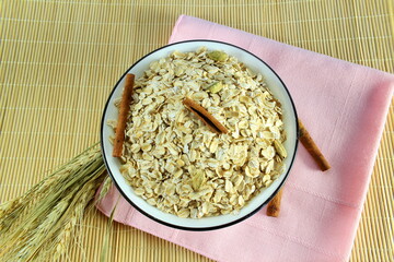 Wall Mural - Dry rolled oatmeal flakes in bowl with cinnamon and oats ears 