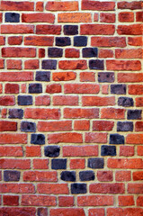 Black bricks pattern on red brick wall.