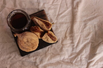 overhead dried figs and fig juice on wooden dish with brown background. space for text, backlight