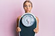 © Krakenimages.com - Beautiful blonde woman holding weight machine to balance weight loss puffing cheeks with funny face. mouth inflated with air, catching air.