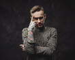 © Fxquadro - Dressed in ragged shirt stylish and bearded hipster with modern haircut poses in dark background