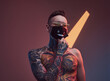 © Fxquadro - Individual and tattooed macho weared with sunglasses and protective mask poses in dark studio room with spotlight and colourful walls.