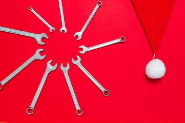 Wall Mural - Wrenches different size decorated with santa claus hat on a red background. New Year banner with tools. Postcard with place for greeting text with industrial holiday concept. Shape of sun. Close-up