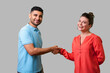 © khosrork - Portrait of lovely young couple in casual wear standing, looking at camera with smile and shaking hands, friendly meeting or acquaintance, greeting. isolated on gray background, indoor studio shot