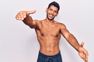 Sticker - Young latin man standing shirtless looking at the camera smiling with open arms for hug. cheerful expression embracing happiness.