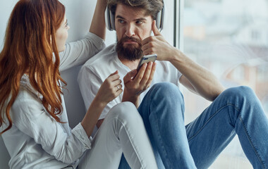 cheerful man and woman listening to music at home near the window rest