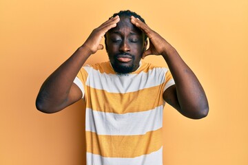 Poster - Handsome young black man wearing casual yellow tshirt suffering from headache desperate and stressed because pain and migraine. hands on head.