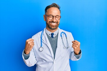 Sticker - Handsome middle age man wearing doctor uniform and stethoscope excited for success with arms raised and eyes closed celebrating victory smiling. winner concept.