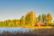View on Scandinavian red holiday cabin by a lake in morning light. Autumn in Sweden