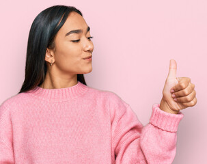 Canvas Print - Young asian woman wearing casual winter sweater looking proud, smiling doing thumbs up gesture to the side