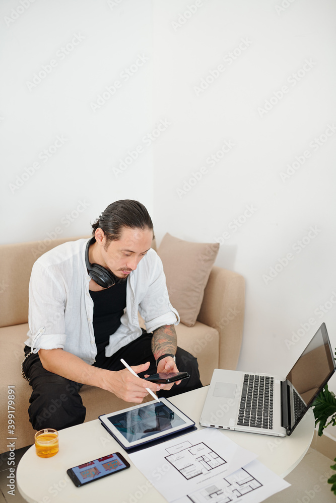 Serious interior designer checking text messages from client when ...