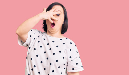 Poster - Brunette woman with down syndrome wearing casual clothes peeking in shock covering face and eyes with hand, looking through fingers with embarrassed expression.