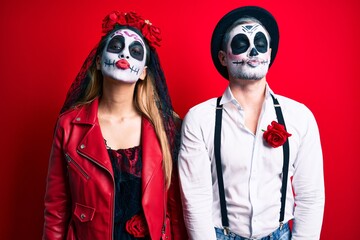 Canvas Print - Couple wearing day of the dead costume over red looking at the camera blowing a kiss on air being lovely and sexy. love expression.