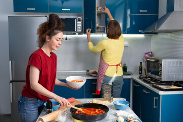 Two young Caucasian women prepare food together in the kitchen. The concept of home-cooked food and LGBT relationships